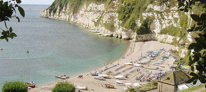 Fishing boats drawn up on the pebble beach at Beer beneath the white chalk cliffs