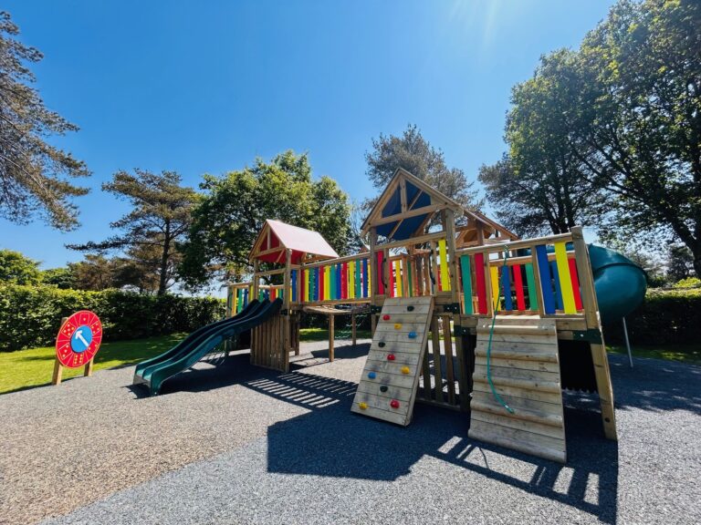 The new timber play park at Oakdown seen across the gravel, with climbing frames, towers and a slide