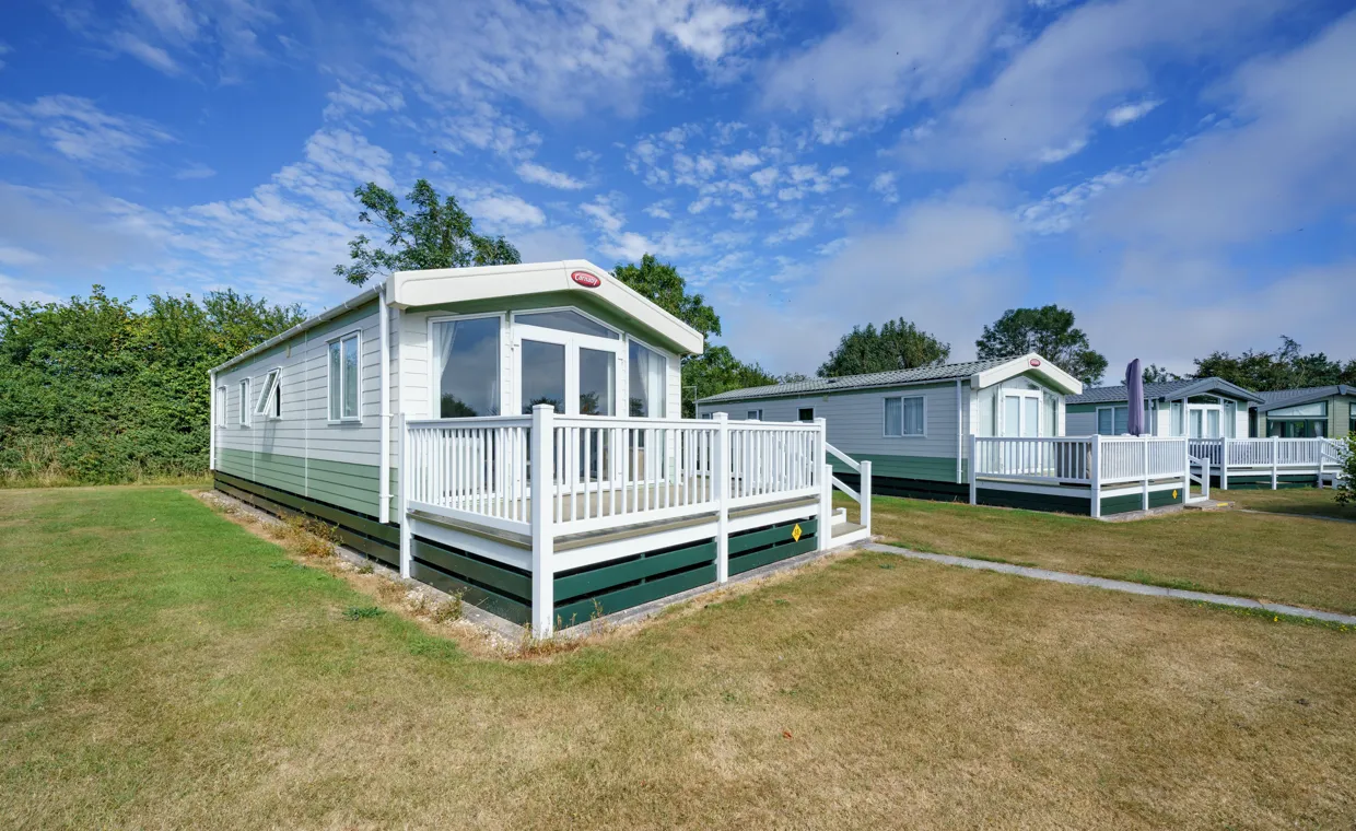 Pine Grove 31 on its pitch with the lawn in front and other holiday homes along the row