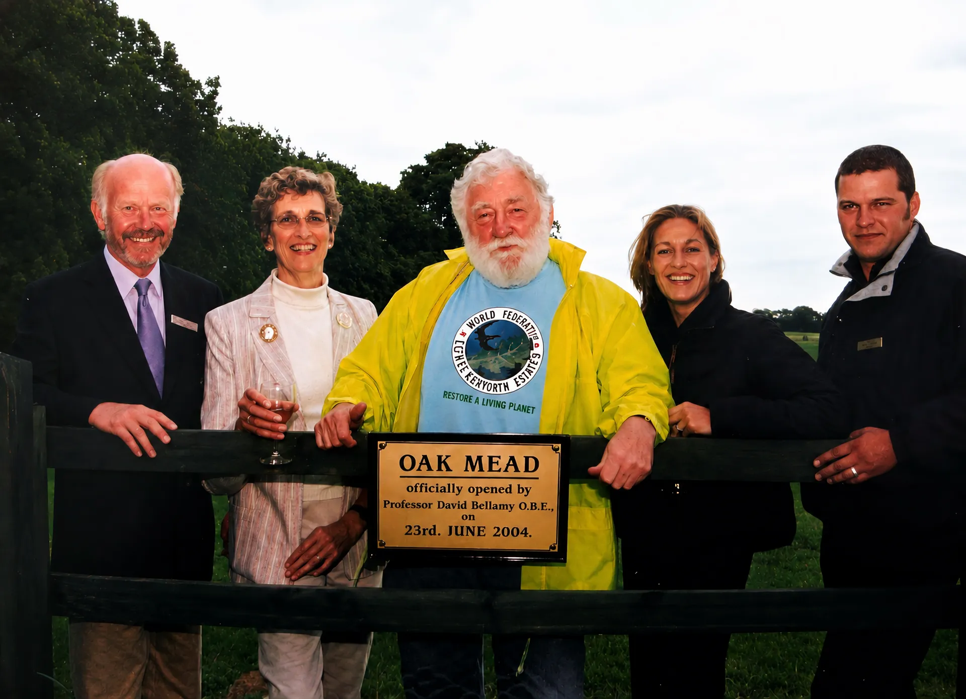 Professor David Bellamy in a yellow jacket, with four others behind the Oak Mead gate, beside the brass plaque marking the official opening
