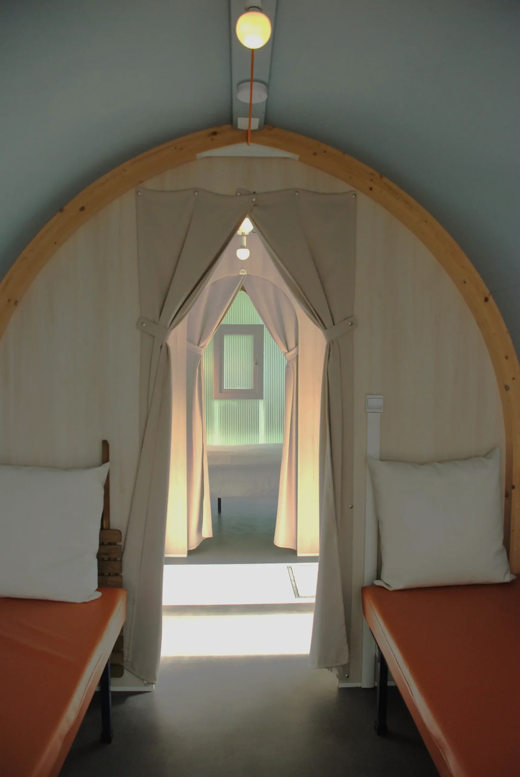 Looking the length of a premier pod between the beds and through the curtains to the door
