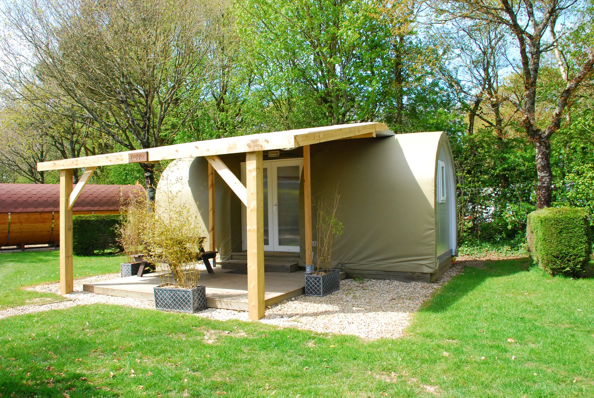A premier pod seen from the side, showing the curved canvas roof and the timber posts of the veranda