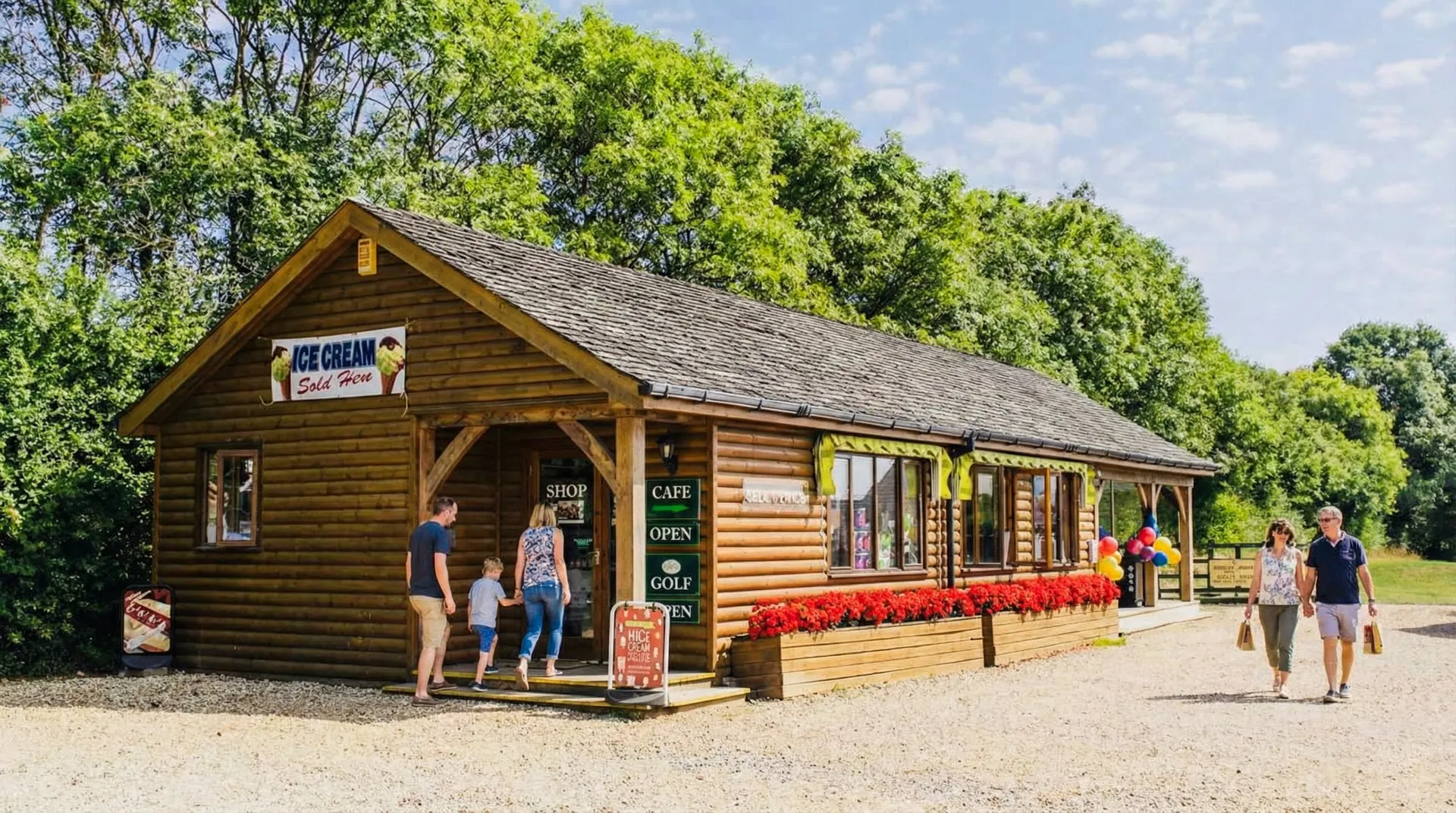 The timber cafe building at Oak Mead, with people at the door and the gravel path running past