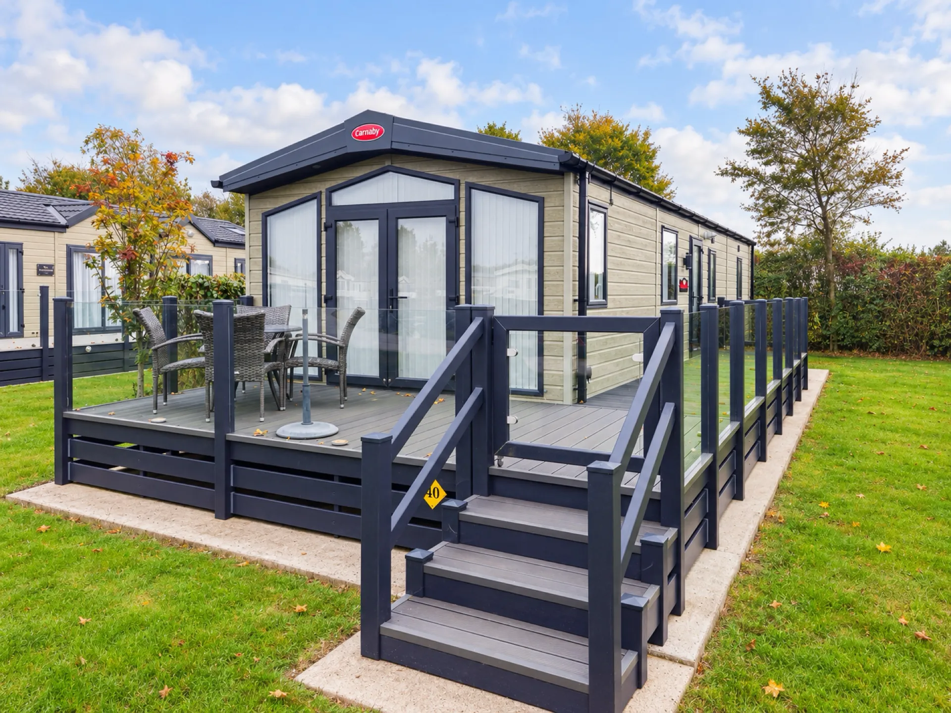 Carnaby Glenmoor at Pine Grove 40 with French doors onto glass-panelled decking and steps down to the lawn, Oakdown Holiday Park